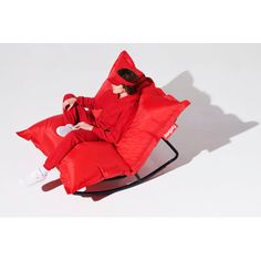 a person sitting in a red chair with pillows on it