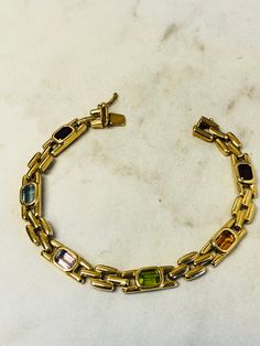 "14kt Yellow Gold Lady's Semi-Precious Gemstone Bracelet in 7\" length consisting of 6- 6mm x 4mm Octagon shape semi-precious gemstones all bezel set. Gemstones include 2- Garnet, 1-Citrine, 1-Peridot, 1- Amethyst and 1- Blue Topaz all faceted for maximum brilliance and sparkle. The chain link style is Panther which is solid and hinged for great flexibility and comfort with a heavy box clasp and fig 8 safety clasp. The total weight of the bracelet is 15.70 grams. This item would Retail for $2,49 Formal Yellow Gold Bracelets With Stones, Classic Yellow Gold Bracelets With Multi-stone, Classic Yellow Gold Multi-stone Bracelets, Formal Gold Bracelets With Gemstone Accents, Formal Yellow Gold Multi-stone Bracelet, Elegant Multicolor Rectangular Bracelet, Classic Gold Multi-stone Bracelets, Elegant Rectangular Multi-stone Jewelry, Rectangular Gemstone Bracelet In Yellow Gold