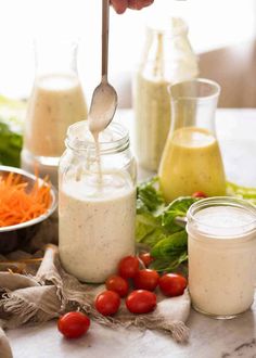 a person spooning dressing into a jar with carrots and parsley on the side