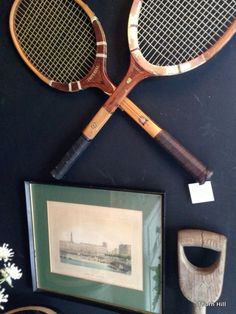 two tennis racquets hanging on the wall next to a vase with flowers