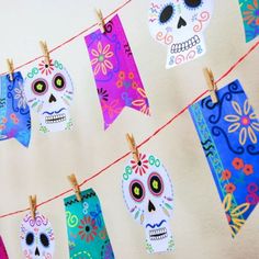 day of the dead decorations hanging on a clothes line with colorful paper skulls and flowers