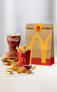 a mcdonald's hamburger, french fries and drink are on the table next to a paper bag