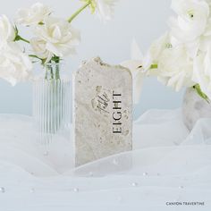 white flowers in vases with the word light written on them next to a tombstone