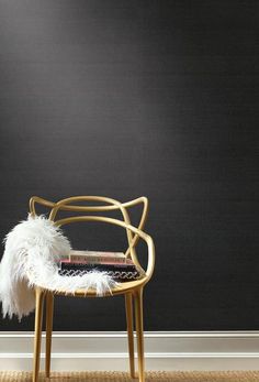 a chair with a book on it sitting in front of a black wall next to a rug