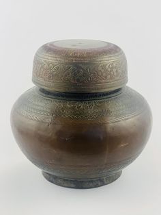 a large brown vase sitting on top of a white table next to a black container