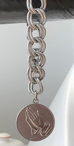 This beautiful Monet bracelet is a perfect addition to any jewelry collection. The sterling silver bracelet features a charming dangle charm with praying hands on the front and the serenity prayer on the back. The bracelet is 6 inches in length and has a double link chain type.  The bracelet is perfect for any occasion, whether it be a Christmas gift, anniversary gift, or birthday gift. It is also signed by the Monet brand, adding a touch of authenticity to the piece. The vintage style and relig Everyday Silver Charm Bracelet With Lobster Clasp, Silver Spiritual Dangle Charms, Spiritual Silver Dangle Charms, Spiritual Silver Jewelry With Dangling Charms, Spiritual Silver Jewelry With Extender, Silver Symbolic Bracelets With Dangling Charms, Symbolic Silver Bracelets With Dangling Charms, Symbolic Silver Bracelet With Dangling Charms, Spiritual Nickel-free Dangle Charm Bracelet