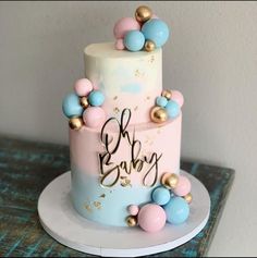 a pink and blue baby shower cake with gold decorations on it's top tier