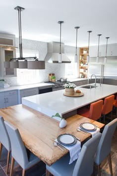 a large kitchen with an island table surrounded by gray chairs and white countertops, along with stainless steel appliances