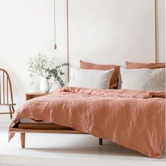 a bed with an orange comforter and two white vases on the side table