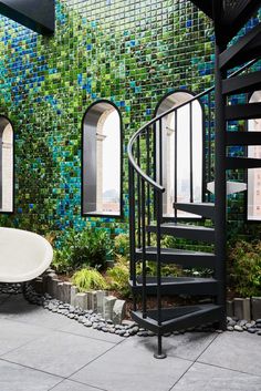 a spiral staircase in front of a tiled wall with green tiles on it and a white bathtub