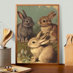 two rabbits sitting next to each other in front of a painting on a table with utensils