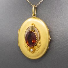 This breathtaking locket is a beautiful product of the Art Nouveau era. The locket features a center madeira citrine measuring 14.61 x 10.87mm, approximately 2ct. The base features a seed oearla nd incredibly cared gold flowers. The locket opens and closes tightly and the inside features two portraits (which can be removed) with the original glass. The locket is crafted in 14k and has an overall appearance, we have not polished it to leave this patina intact. The locket measures 1 7/8" in length Antique Orange Gemstone Jewelry, Heirloom Amber Oval Jewelry, Heirloom Oval Amber Jewelry, Antique Oval Orange Jewelry, Victorian Gold Citrine Jewelry, Victorian Citrine Gold Jewelry, Victorian Style Gold Citrine Jewelry, Antique Orange Oval Jewelry, Oval Citrine Antique Jewelry