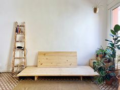 a wooden bench sitting in the middle of a living room next to a potted plant