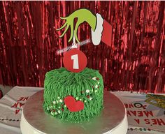 there is a cake that has been decorated with green grass and red hearts on it