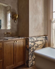 a bathroom with marble counter tops and wooden cabinets, along with a white bathtub