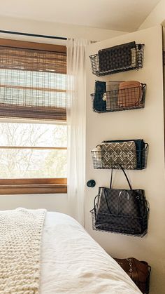 a bedroom with three baskets on the wall and two purses hanging up against the wall