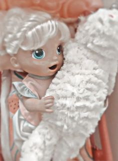 a doll with blonde hair and blue eyes holding a white teddy bear in her arms