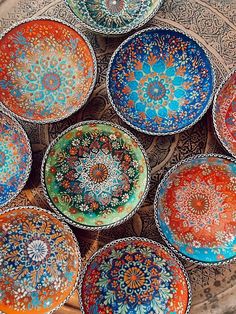 many colorful plates are arranged in a circle on a table top, with intricate designs