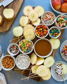 apples, cereals and candy are arranged in bowls on a cutting board next to other foods