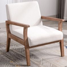 a white chair sitting on top of a rug next to a wooden frame and window