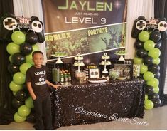 a young boy standing in front of a table with balloons