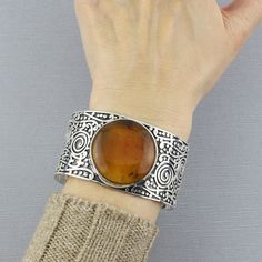 This chunky cuff bracelet knows how to get everyone’s attention with its sophisticated amber stone, is super-easy to slip on and wear, and is undeniably chic. Whether you're buying it for yourself or as a thoughtful gift, this artisan bracelet is a symbol of timeless beauty and craftsmanship that you'll cherish for years to come. Gemstone - Natural Amber 925 Sterling Silver Approx. 6" L (end to end) x 1.4" W Handcrafted in Chiapas, Mexico Chunky Cuff Bracelet, Silver Bracelets For Women, Artisan Bracelets, Natural Amber, Amber Stone, Sterling Silver Bangles, Gemstone Bracelets, Silver Bangles, Silver Bracelets