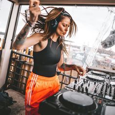 a woman with headphones on standing in front of a dj set