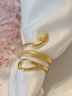 Make a bold style statement with our 18K Gold Filled Snake Ring. This stunning piece features an adjustable serpent design, crafted from durable stainless steel and filled with lustrous 18K gold. The spiral shape of the ring wraps elegantly around the finger, making it a striking and elegant choice for any jewelry collection. ✨Product Features ✨ * Stainless Steel - 18k Gold Filled * Necklace Length:  💎 Material 💎 * Stainless Steel * Our products are produced by hand in our workshops. * Our jewelry is made of handmade All the rings, bracelets, piercings, necklaces, and earrings we designed as Unique Jewelry were produced for you with modern lines to compliment your elegance. 👻 🚚 Shipping & Production Time 🏭 🎁 All of our items will be sent in a beautiful jewelry box ready for gift. 🚚 Adjustable Spiral Snake Ring As Gift, Serpent Ring, Spiral Shape, Snake Jewelry, Snake Ring, Minimalist Gifts, Wrap Rings, Stackable Rings, Gold Filled