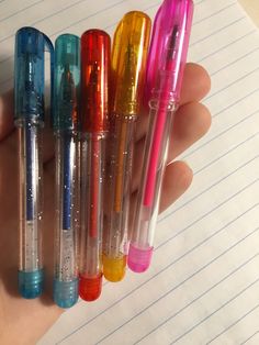 four different colored pens are in the palm of someone's hand