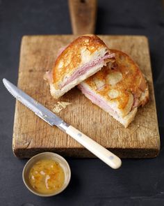 a sandwich cut in half sitting on top of a cutting board next to a knife