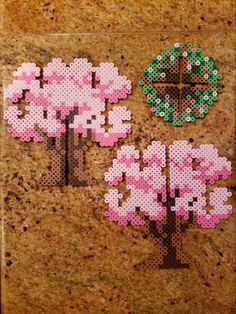 the cross stitch artwork is made with pink flowers and green leaves on a cork board