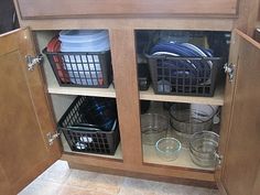 a kitchen cabinet with baskets and dishes in it