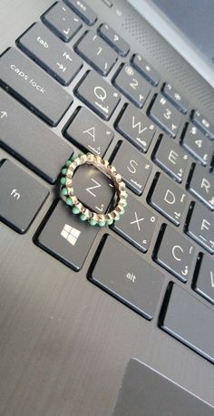 a ring is sitting on the keyboard of a laptop that has it's keys missing