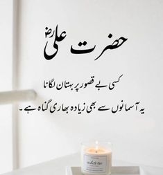 a candle sitting on top of a white table next to a wall with arabic writing