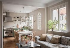 a living room filled with furniture next to a kitchen and dining room table in front of a window