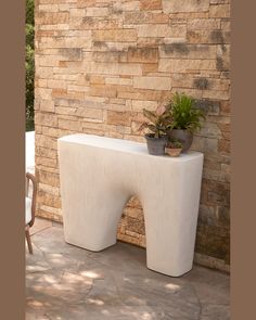 a planter sitting on top of a white table next to a brick wall and chair