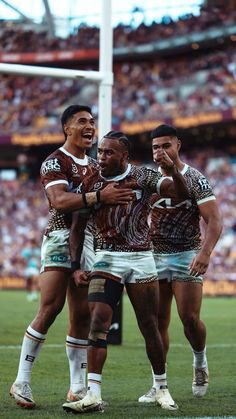 three rugby players are congratulating each other in front of the crowd at a stadium