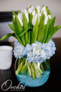 a glass vase filled with white and blue flowers