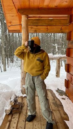 a person standing on a wooden platform in the snow holding a camera up to their face