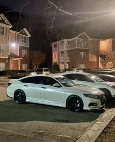 two white cars parked next to each other in front of apartment buildings at night time