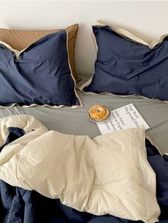 an unmade bed with blue sheets and pillows