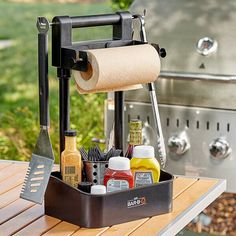 an outdoor grill with cooking utensils and spices on the table next to it