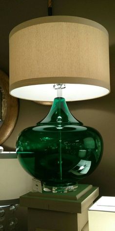 a green glass lamp sitting on top of a table next to a white light shade