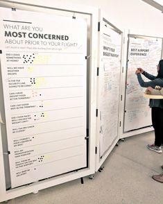 two people standing in front of a whiteboard with writing on it and another person pointing at the board