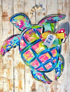 a colorful turtle made out of paper on top of a wooden table with beads and other items