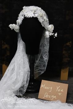 a mannequin wearing a white veil with flowers on it and a card that says marry you design