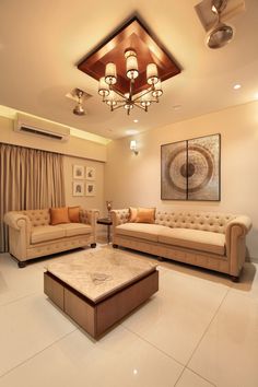 a living room filled with furniture and a chandelier hanging from the ceiling above