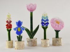 four vases with flowers in them sitting next to each other on a white surface