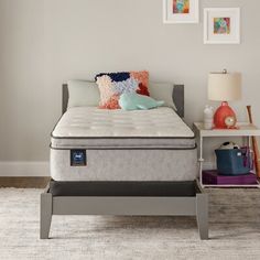 a bed with a mattress and pillows on top of it next to a night stand