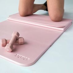 a woman laying on top of a pink mat with two dumbs attached to it